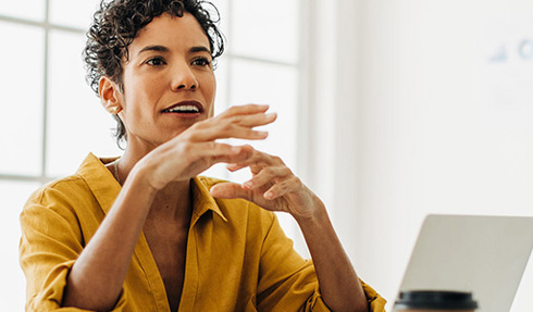 person speaking in meeting room with laptop