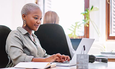 person at desk writing on laptop in an office