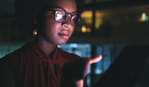 Woman with glasses looking at computer screen.